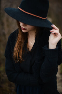 Female model hiding her eyes under stylish black hat