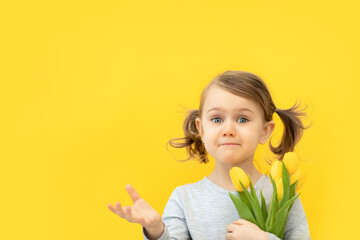 Surprised child holds bouquet of yellow tulips. Spring, mother's day concept. Banner, copy space...
