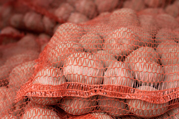 Freshly harvested and washed potoatoes in a net pack in a greengrocer's. Background image