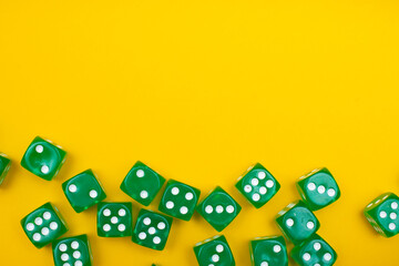 Green gaming dices on yellow background. Flat lay, place for text. Table games concept, board game for the whole family