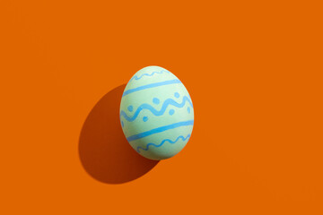 Easter egg. Spring holiday. Festive decoration. Gift card. Abstract background. Colorful blue paschal symbol with ornament pattern isolated on orange copy space.