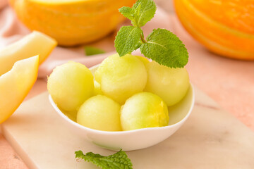Bowl with sweet melon balls on color background