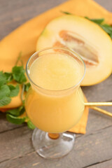 Glass with melon smoothie on wooden background