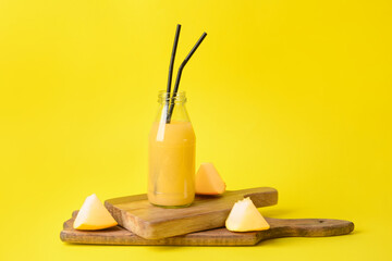 Bottle with melon smoothie on color background