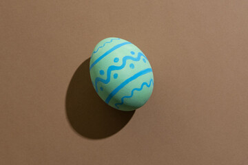 Easter egg. Festive decoration. Spring holiday. Gift card. Colorful light green paschal symbol with blue ornament pattern isolated on beige copy space.