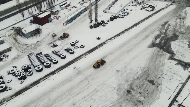 bulldozer is driving on a road covered with snow. aerial shooting