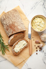 Slices of fresh bread with garlic butter on light background