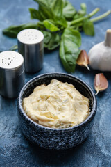 Bowl with tasty garlic butter on color background