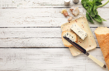 Spreading of garlic butter onto slice of bread on light wooden background