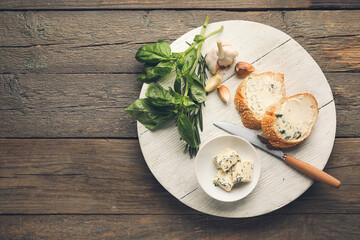 Slices of fresh bread with garlic butter on wooden background