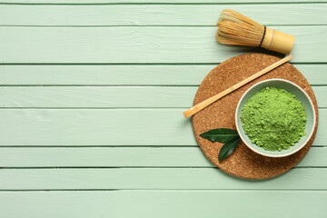 Bowl with powdered matcha tea, chashaku and chasen on color wooden background