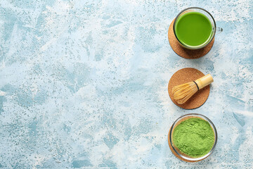 Cup of matcha tea, powder and chasen on color background