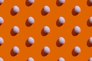 Easter seamless pattern. Festive banner. Holiday decoration. Abstract background. Colorful eggs of pink and green striped ornament isolated on orange.