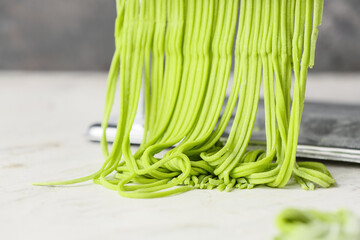 Pasta machine with dough on light table, closeup