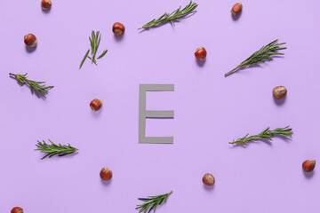 Letter E with healthy nuts and herbs on color background