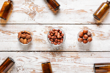 Bowls with different healthy nuts and oil on white wooden background