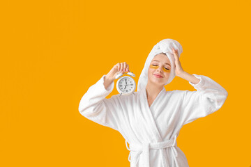 Beautiful young woman with alarm clock on color background