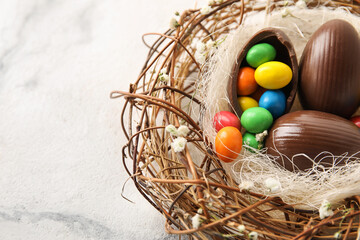 Nest with chocolate Easter eggs on light background, closeup