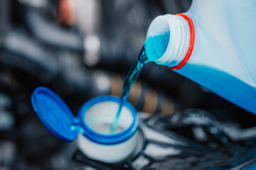 Pouring antifreeze. Filling a windshield washer tank with an antifreeze in winter cold weather.