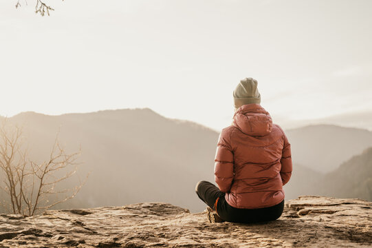 Woman enjoying the sunset in nature on the edge of a rock cliff. Woman hiker enjoys mountains view