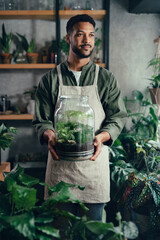 Shop assistant holding terrarium in indoor potted plant store, small business concept.