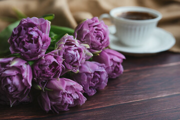 Spring flowers. Bouquet of tulips on a wooden background. Coffee and tulips. Flatley.