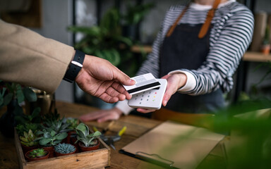 Customer paying in potted plant store, small business and contactless payment concept. - obrazy, fototapety, plakaty