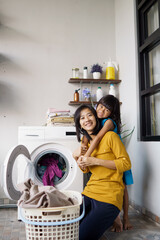 Beautiful young asian woman and child girl little helper are doing laundry at home.