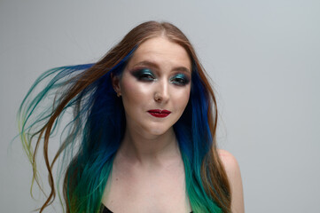 Portrait on a white background of a caucasian brunette model with long dyed hair and bright makeup