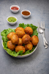 bread rolls stuffed with potatoes placed on a lettuce leaf served with green and red sauces