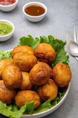 bread rolls stuffed with potatoes placed on a lettuce leaf served with green and red sauces