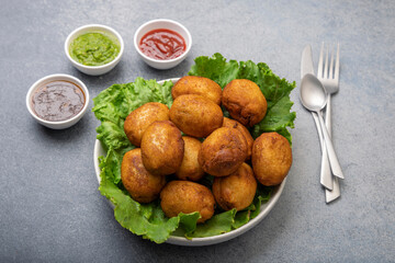 bread rolls stuffed with potatoes placed on a lettuce leaf served with green and red sauces