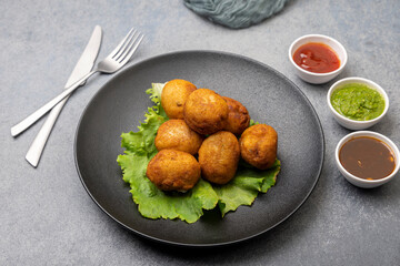 bread rolls stuffed with potatoes served with green and red sauces