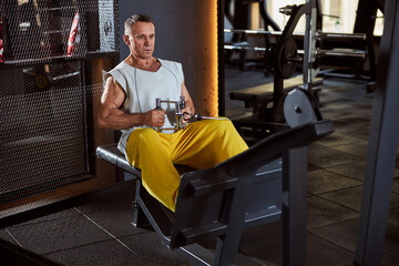 Naklejka premium Reserved sporty man on a sitting rowing machine