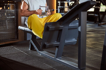 Fototapeta premium Fit man exercising on a sitting rowing machine at gym