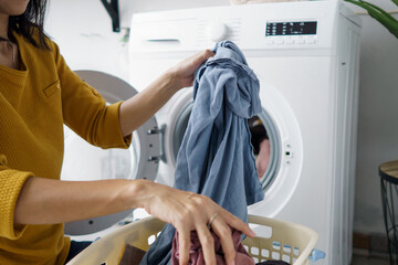 close up of woman in front of the washing machine doing some laundry loading clothes inside