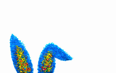  Happy Easter with blue colored coconut flakes and colorful sweet candy bunny ears on white Background. Happy  Easter concept. Minimal concept. Sweet candy concept. Flat lay. Copyspace for text. 