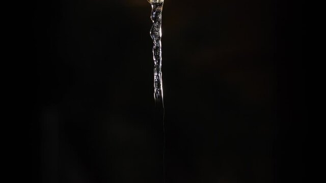 Time lapse sequence of a growing icicle in front of a black background