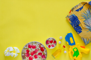 Songkran festival background with flowers and scented water to give blessing and accessories to play water on yellow background.