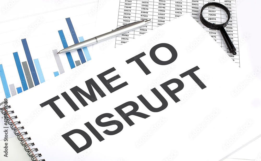 Poster in the notebook, the text time to disrupt , next to magnifier and a pen, the background is graphics.