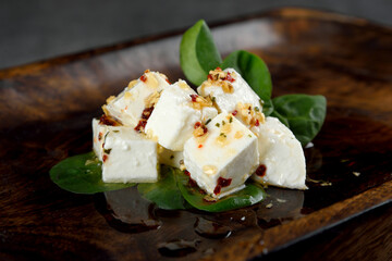 Feta cheese served with fresh vegetables on dark wooden background