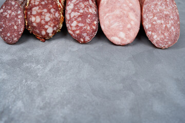 Assortment of raw smoked sausages on a gray table with copy space.