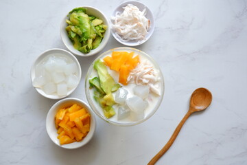 a glass of es teler or various fruits with coconut milk soup and ice cubes