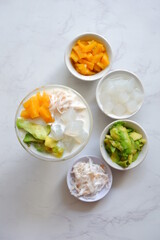 a glass of es teler or various fruits with coconut milk soup and ice cubes
