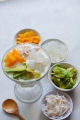 a glass of es teler or various fruits with coconut milk soup and ice cubes