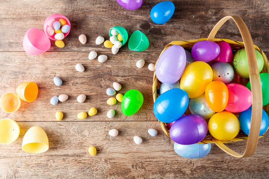 Flat lay image of plastic easter eggs being filled with chocolates before easter egg hunt. It is a fun activity for children who search for eggs and get the chocolates.