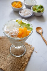 a glass of es teler or various fruits with coconut milk soup and ice cubes