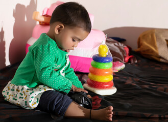 Asian Indian baby girl portrait closeup playing with toys. A cute baby girl .