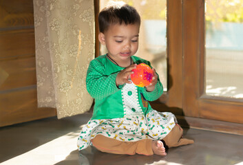 Asian Indian baby girl portrait closeup playing with toys. A cute baby girl .