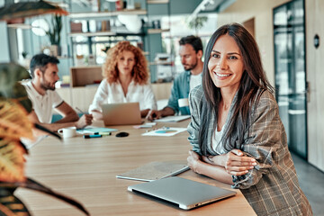 Cheerful businesswoman standing at table in office